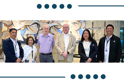 Six professionals standing together for a group photo in a modern lobby with a mural behind them.