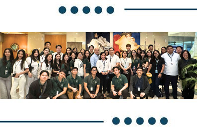 Group photo of a diverse team of coworkers posing together in a corporate office setting, some standing and some kneeling, with name badges visible.