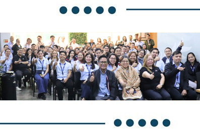 Group of diverse attendees posing for a large photo at an event, many smiling and seated in front row.