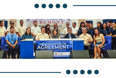 Group photo of officials and attendees at a Memorandum of Agreement signing ceremony, with a banner reading 'Memorandum of Agreement' in front.