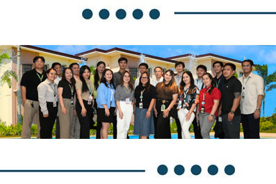 Diverse group of around 20 people standing together outdoors in front of a building, posing for a team photo.