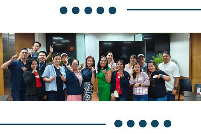 Diverse group of coworkers posing together in a conference room, many giving thumbs up and smiling for a team photo.