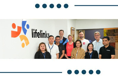 Group of diverse Lifelinks staff posing for a team photo in front of the Lifelinks logo.