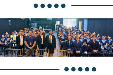 Group photo of students in blue uniforms with several adults in the front row inside a large hall/venue for a class event.
