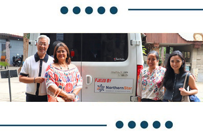Five adults smiling and posing in front of a white service van with a Northern Star logo on the side.