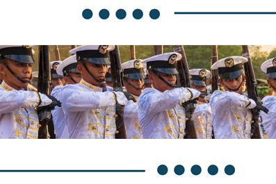 Row of soldiers in white ceremonial uniforms holding rifles in a synchronized drill.