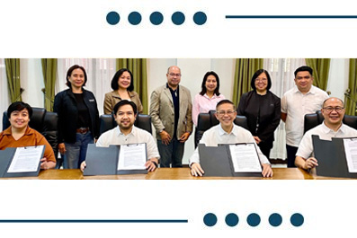 Group of ten people in a formal setting, smiling while displaying signed documents at a long table.