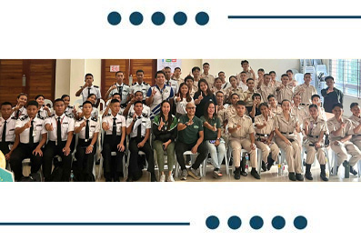 Group of students and instructors posing for a class photo in a hall, many in uniforms and smiling.