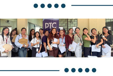 Group of diverse students standing together indoors, holding papers and folders, posing for a class or program photo in front of a DTC sign.