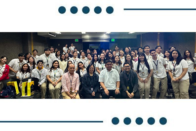 Group photo of about 40 people in a conference room posing for a group shot, many wearing lanyards and name badges.
