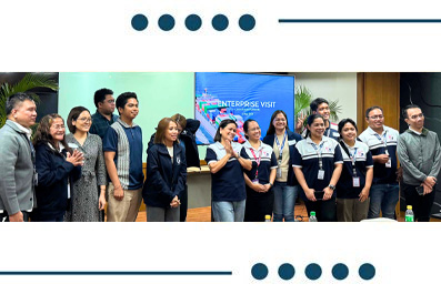 Diverse professionals posing for a photo during an enterprise visit in a conference room, with a banner reading 'Enterprise Visit' in the background.