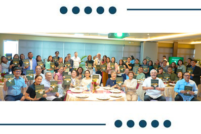 Large group of people posing for a group photo around a banquet table at an indoor event, smiling for the camera.