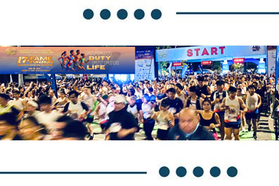 Massive crowd of runners at the starting line of a marathon, with a 'START' banner overhead and banners along the route.