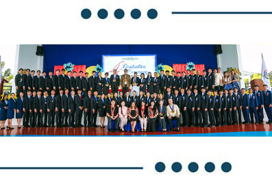 Large group of students in suits and dresses posing for a ceremony photo on a stage with a blue backdrop.