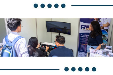 Group of four people gathered around a flight simulation setup at a booth, watching a monitor displaying a scene at an expo display edge.