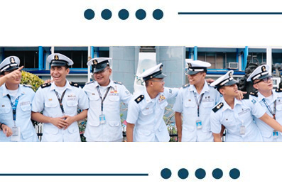 Group of naval officers in white uniforms standing outdoors, smiling and talking together.