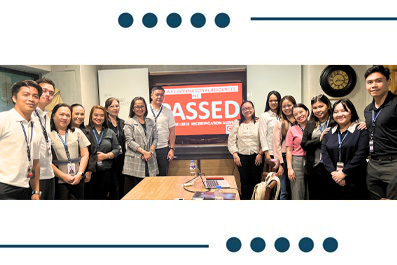Diverse group of professionals posing for a group photo in a conference room, with a red banner in the background.