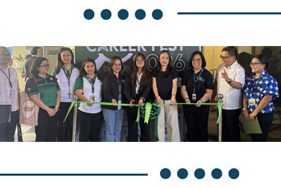 Group of people at a ribbon-cutting ceremony, holding a bright green ribbon in front of a banner at an indoor event.