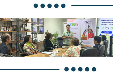 Group of colleagues in a conference room watching a presenter standing by banners during a meeting.