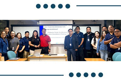 Group of professionals posing for a photo in a classroom during a training session, with a presentation screen behind them.