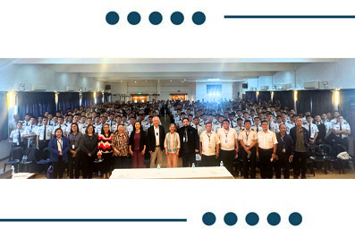 Large group of professionals posing for a group photo in a conference hall, with a lectern visible at the front.