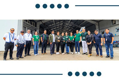 Group of professionals posing outside a large hangar for a team photo.