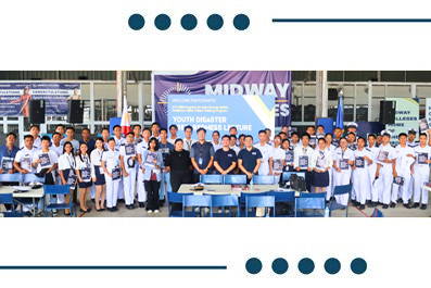 Group of students in uniforms posing with adults in front of a school banner reading 'Youth Disaster Risk Reduction' during a group photo.