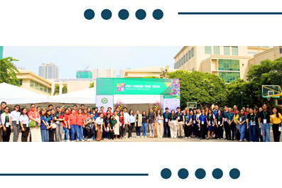 Large diverse group posing for a photo at an outdoor community event, with a bannered stage and tents in the background.