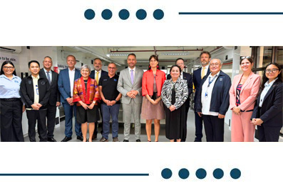 Group of diverse professionals in business attire posing for a group photo in an office hallway.