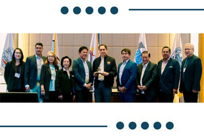 Group of professionals in business attire posing for a photo, with one person in the center holding a trophy at a formal ceremony.