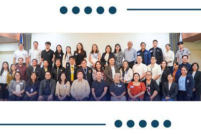 Large group of diverse professionals posing for a group photo at a conference or workshop indoors.