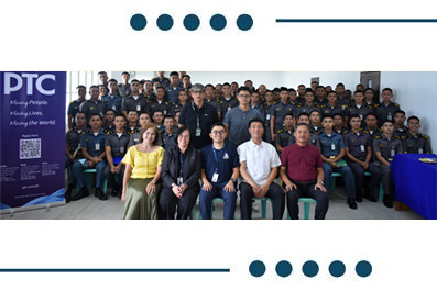 Group of people posing for a photo at a training event, with a PTC banner on the left.