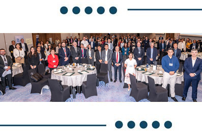 Large group of professionals posing for a formal banquet photo, standing behind round tables set with meals in a conference-style hall.